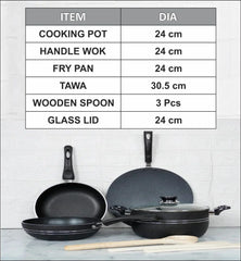 Set of black non stick cookware including a frying pan, wok, tawa, wooden spoon, and glass lid on a white surface with a tiled wall background.